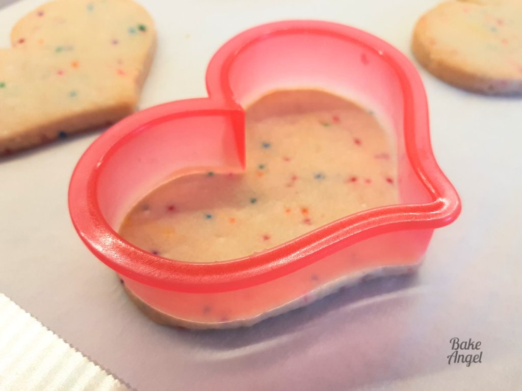 Side view of funfetti no spread sugar cookies, with one cutter on a cookie to show its sharp edges.