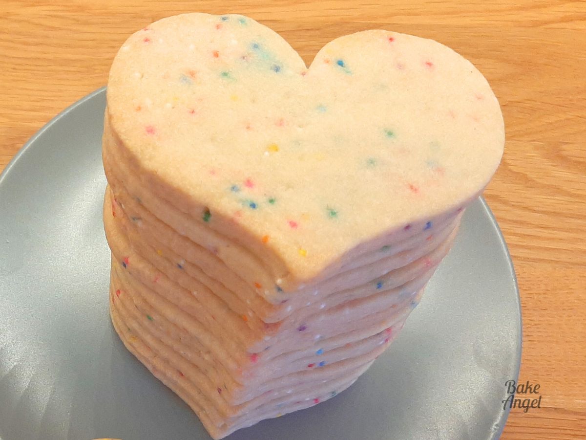 A stack of heart shaped funfetti sugar cookies on a blue plate.