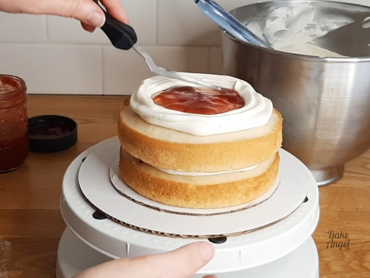 Spreading jam in the middle of the second layer cake. 