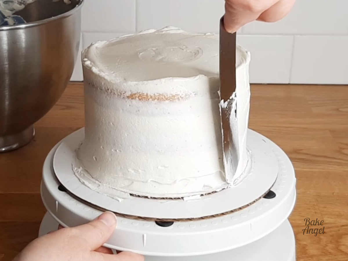 Smoothing buttercream on to the side of the cake with a spatula. 