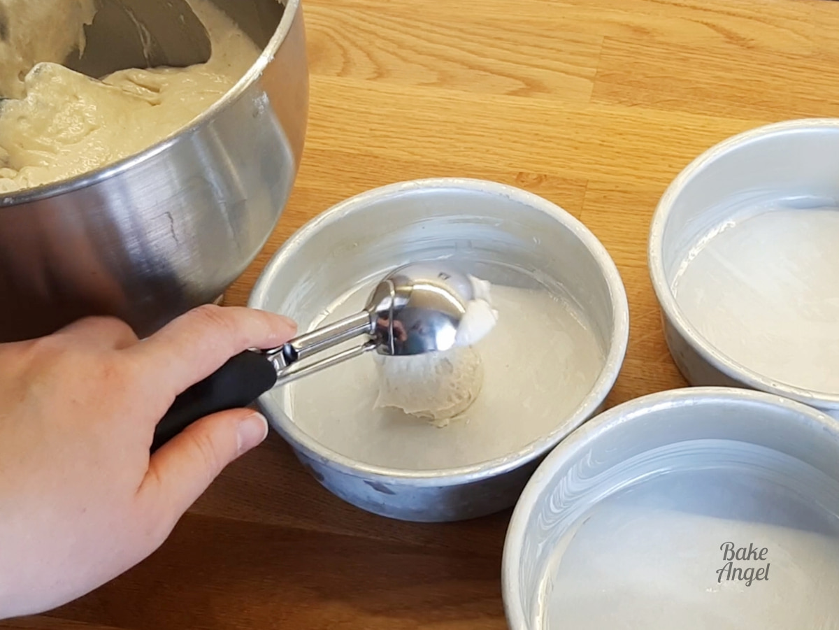 Using an ice cream scoop to fill the cake pans. 