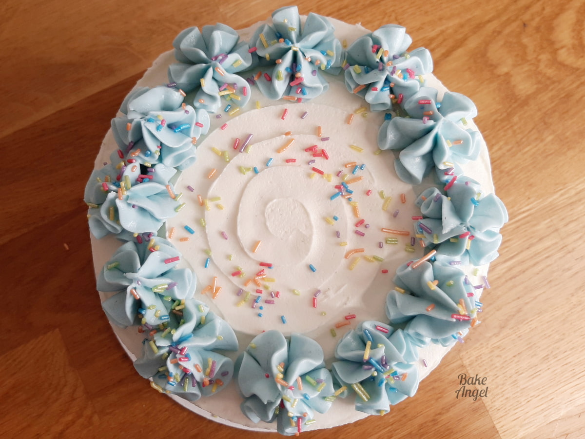 Showing the top of the cake with its blue swirls and sprinkles. 