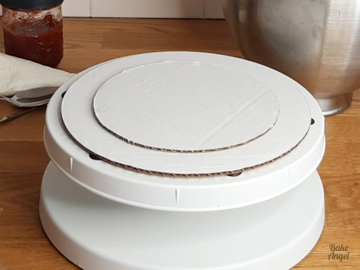 Showing two cake circles on a turntable, ready to stack the vanilla cake. 