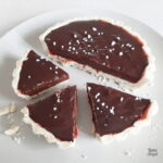 Close up of a chocolate ganache tart with half cut up in to portions.
