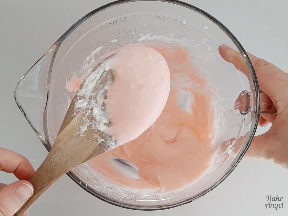 Showing the pink colouring of the coconut ice mixture on a wooden spoon. 