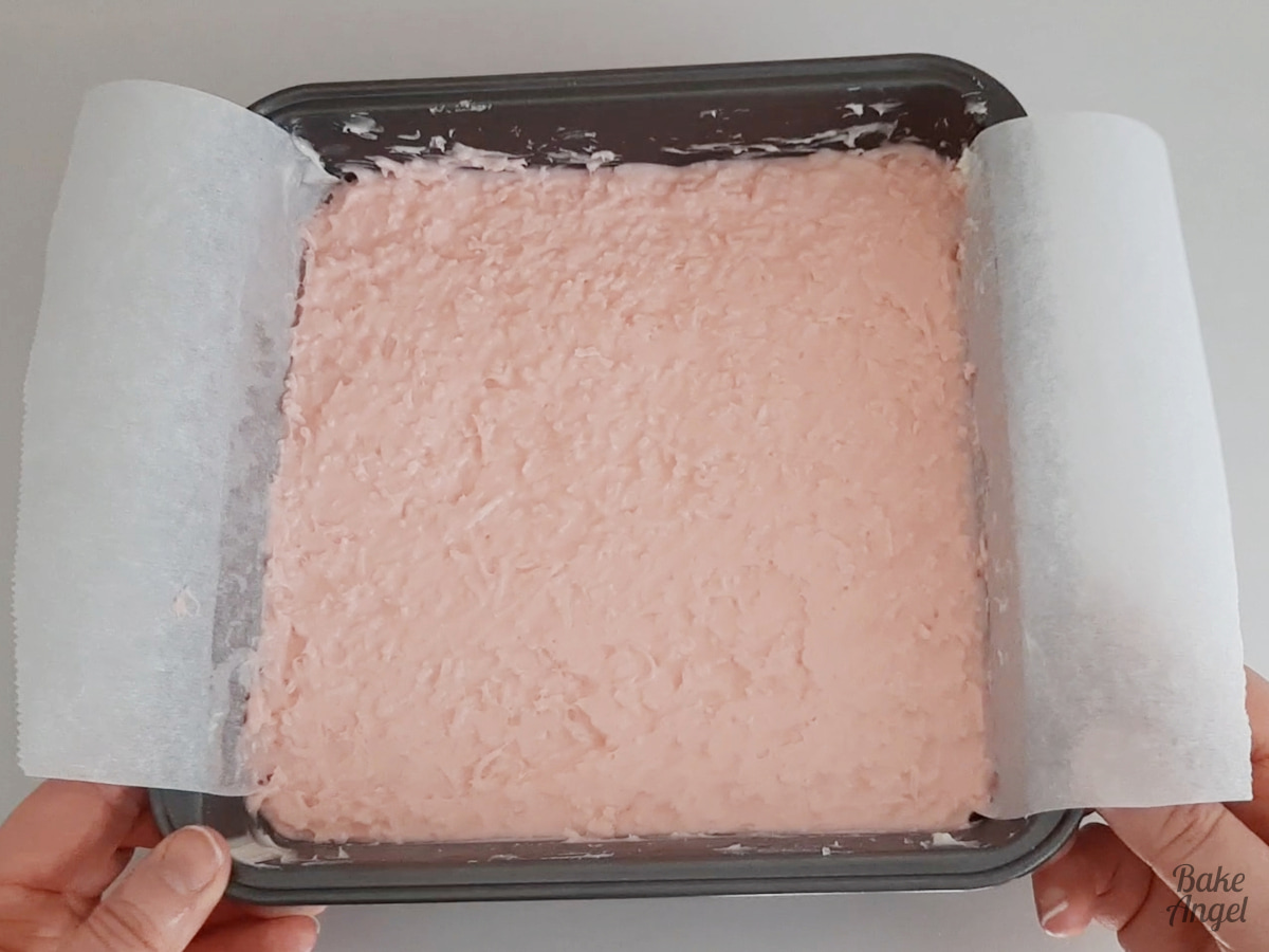 Holding a baking pan with freshly spread coconut ice in it. 