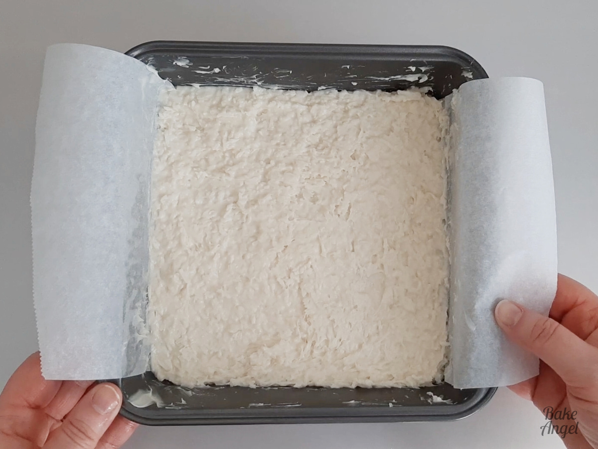 Showing the layer of white coconut ice in the baking pan once spread out evenly. 