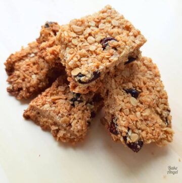 Close up of a stack of cranberry granola bars on a wooden counter.