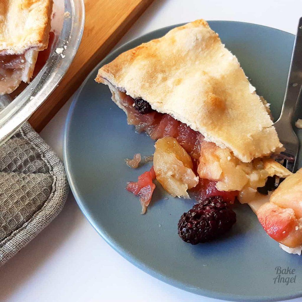 A slice of Apple Blackberry pie on a plate with a fork. 