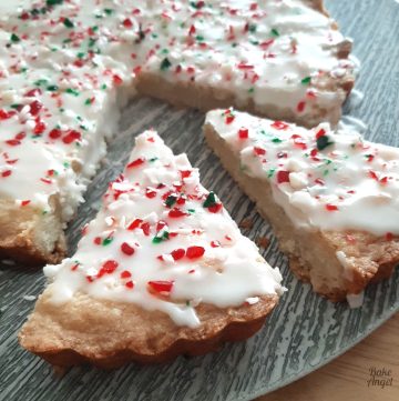 Close up of Candy Cane Shortbread wedges topped with white icing on a grey plate.