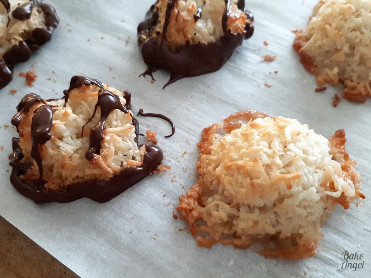 No dairy gluten free Coconut macaroons on parchment paper. Some are coated in chocolate. 