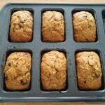 Close up of 6 mini banana bread loaves in a baking tray after baking.
