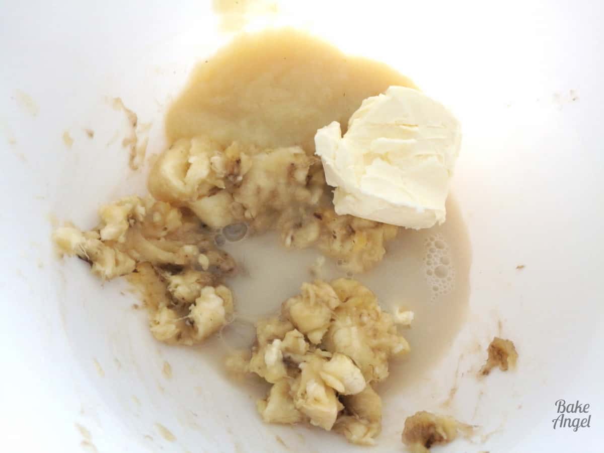 Close up of milk, butter and mashed bananas in a white mixing bowl. 