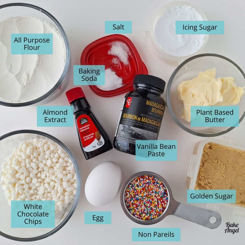 Various bowls and containers of ingredients that are needed to make Disney inspired funfetti cookies on a white countertop.