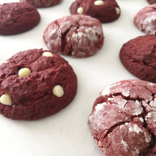 Close up of 3 types of red velvet cookies on parchment paper.