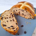 Close up of a vegan giant hot cross bun loaf sliced on a blue plate.