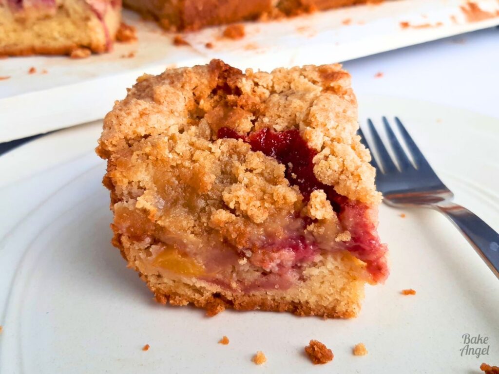 Slice of strawberry peach crumble cake with golden topping, easy dairy free Mother’s Day bake.