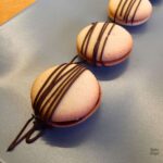 Three marzipan cookies decorated with chocolate on a blue plate.