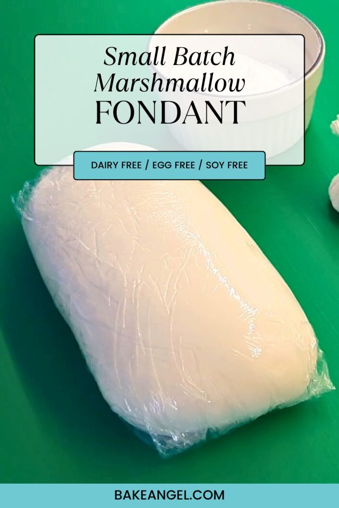 A small batch of homemade marshmallow fondant, wrapped in cling film, on a green board.