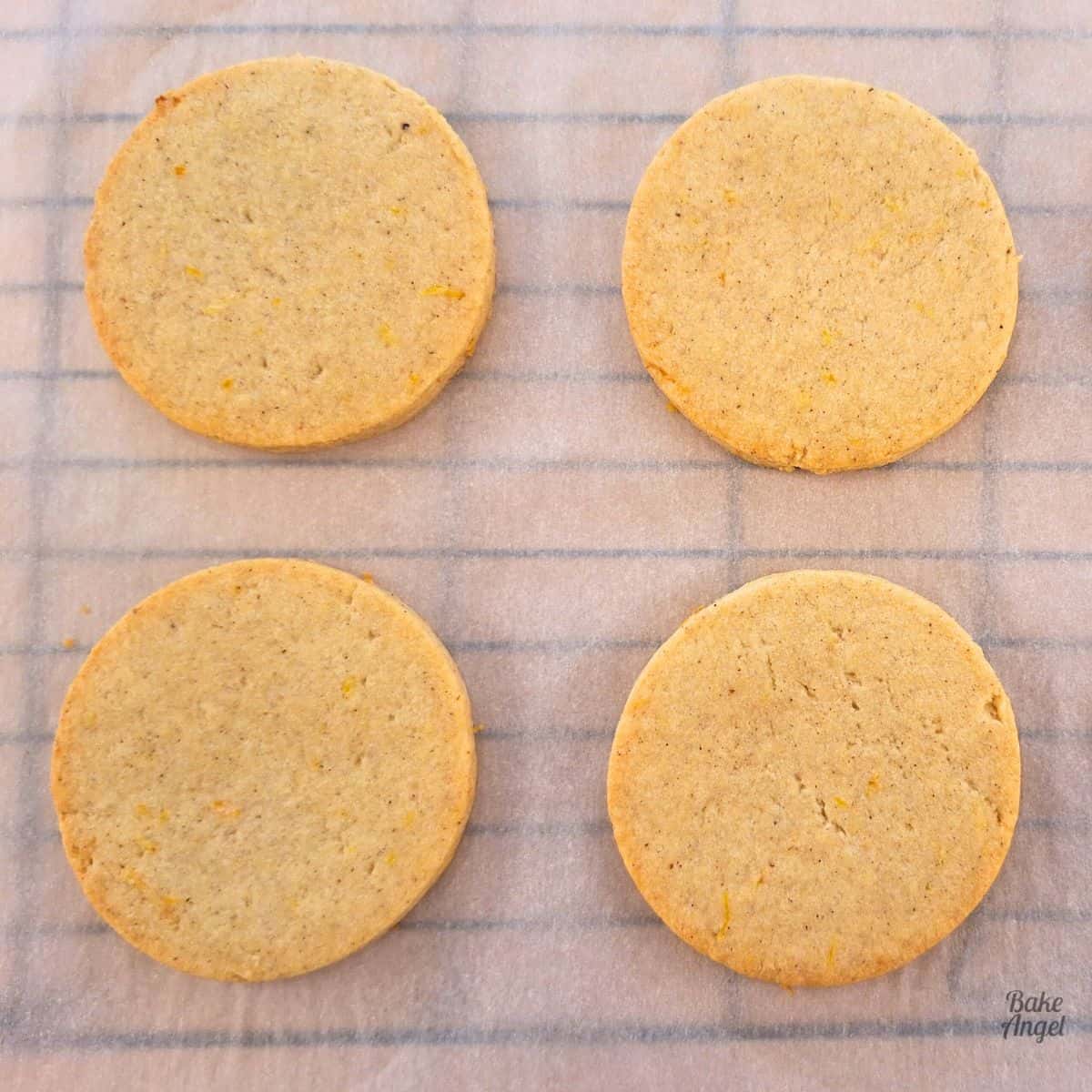 Four Orange Spice Sugar Cookies on parchment paper.