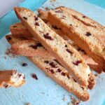 Close up of slices of orange cranberry biscotti on a blue tray.