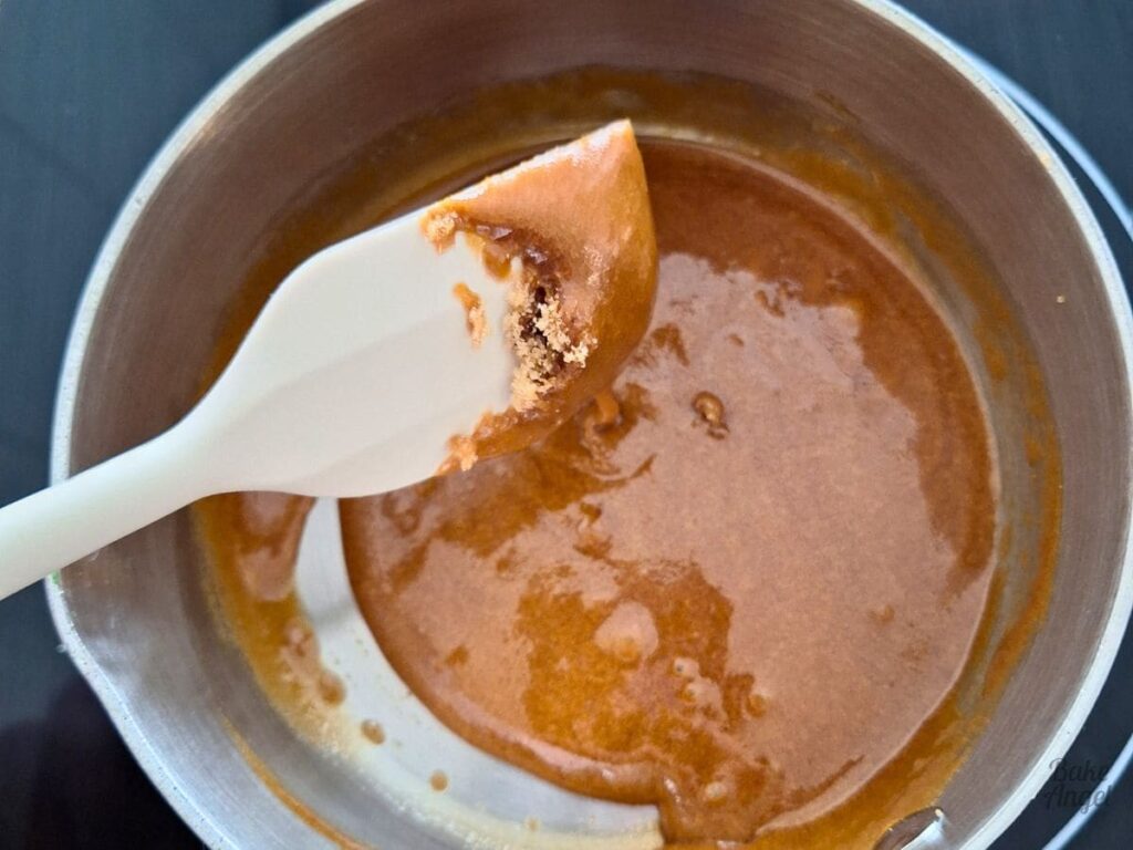 Homemade caramel sauce cooking in saucepan for peach upside down cake.