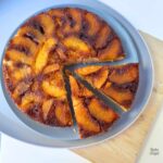 Close up of a peach upside down cake with two slices cut.