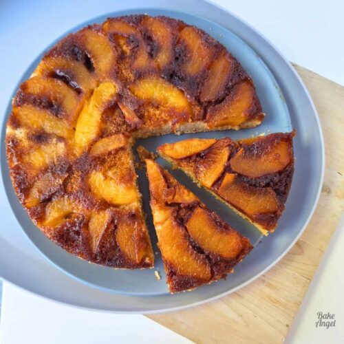 Close up of a peach upside down cake with two slices cut.