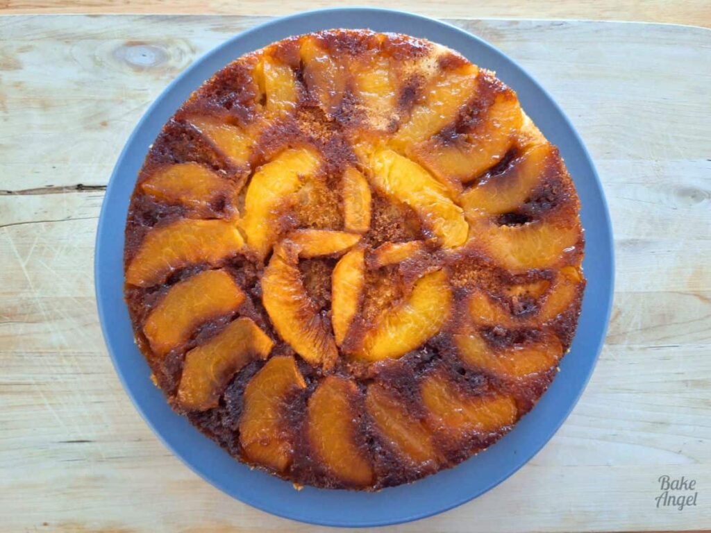 Caramelized peach upside down cake after being flipped from the pan onto a blue plate.