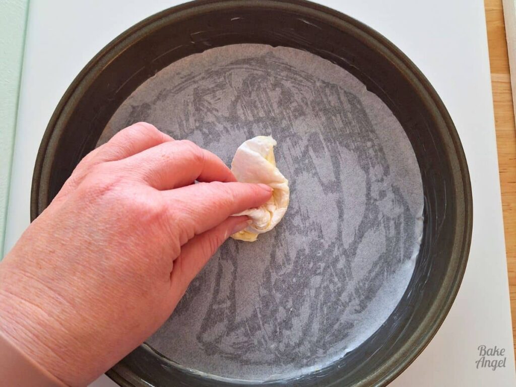 Round cake pan lined with parchment paper for peach upside down cake.