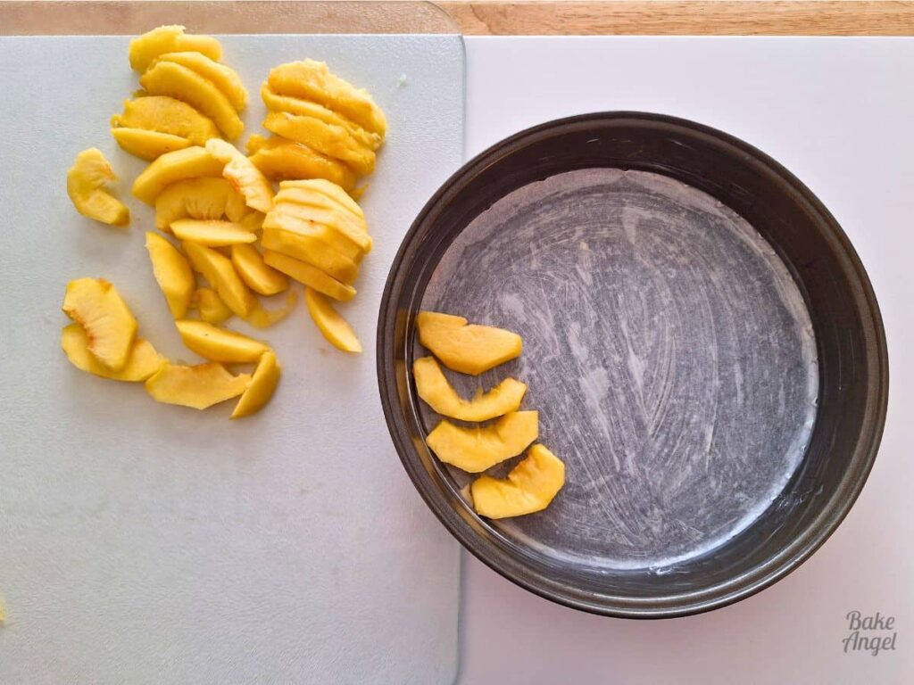 Fresh peach slices arranged in a baking pan for upside down cake.