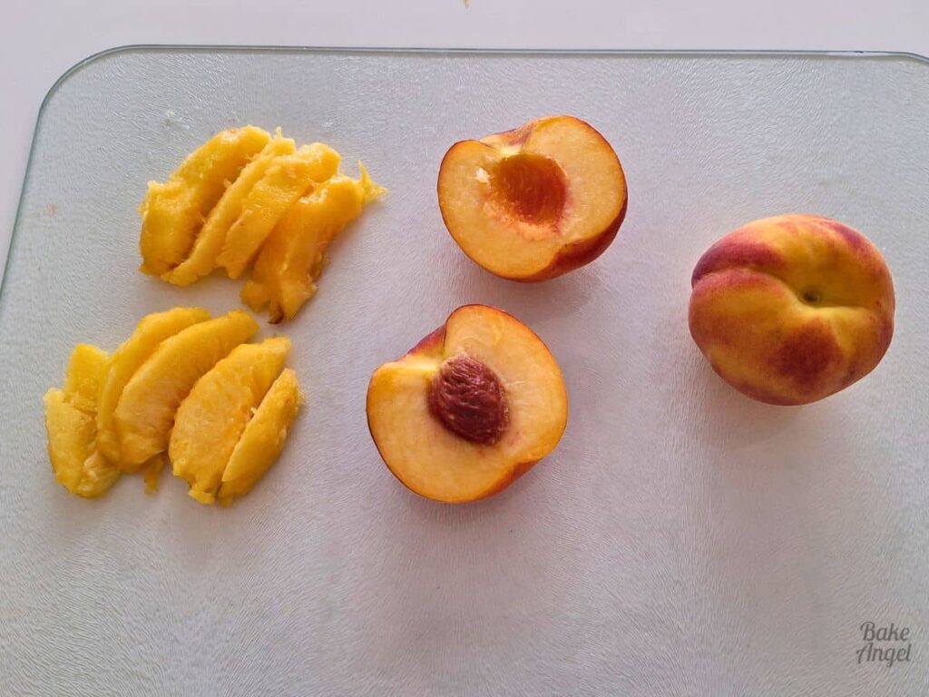 Peaches cut in half and slices on a cutting board for peach upside down cake topping.