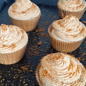 Close up of Vegan Biscoff Cupcakes dusted with crushed biscoff cookies on a tray.