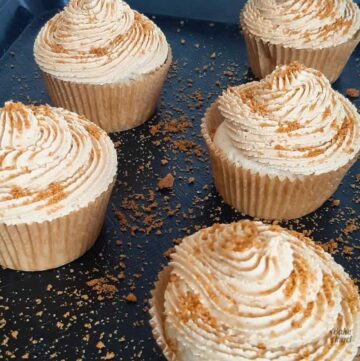Close up of Vegan Biscoff Cupcakes dusted with crushed biscoff cookies on a tray.