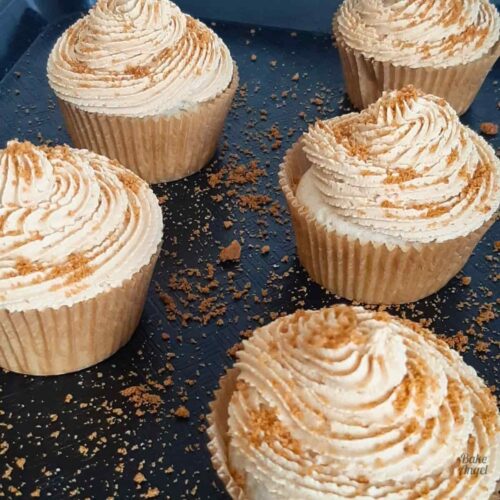 Close up of Vegan Biscoff Cupcakes dusted with crushed biscoff cookies on a tray.