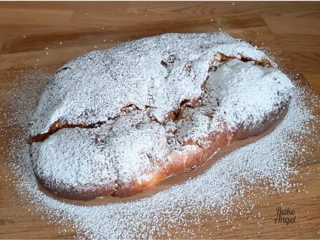 A loaf of stollen dusted heavily with icing sugar, which resembles snow.