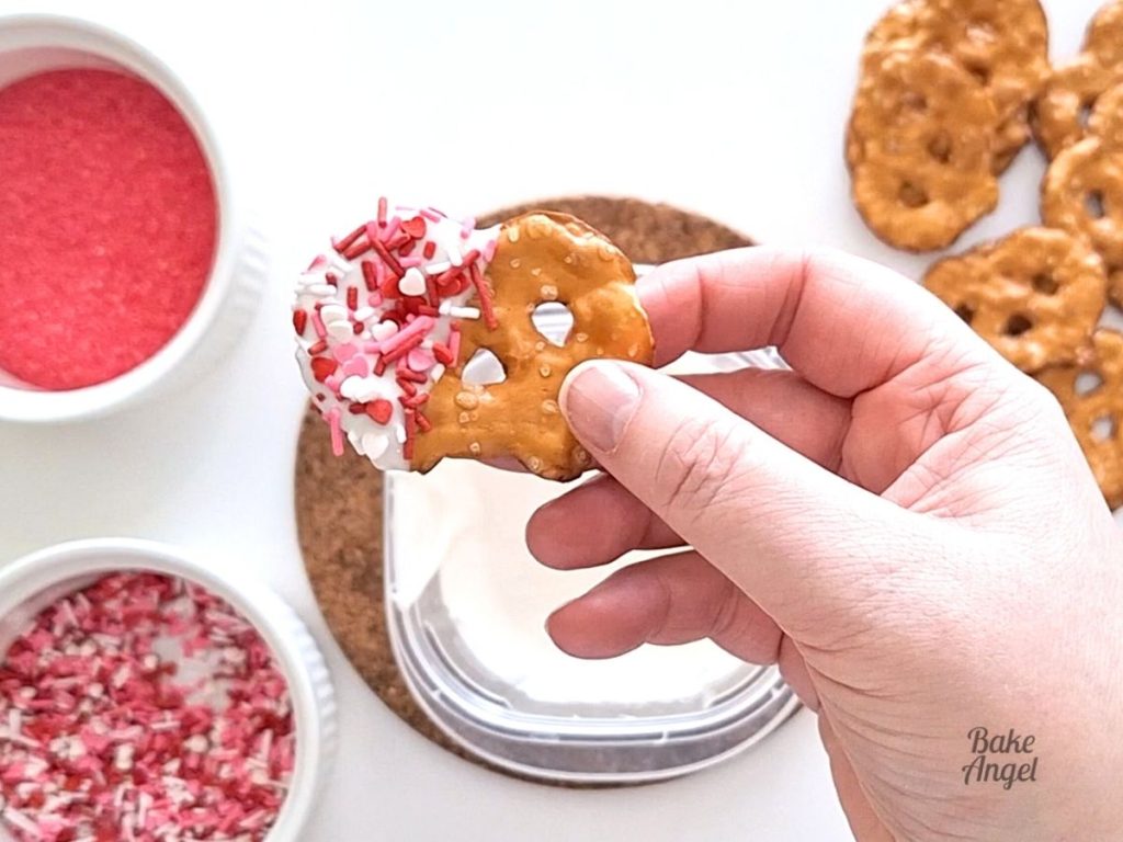 Close up of a white chocolate dipped pretzel with sprinkles.