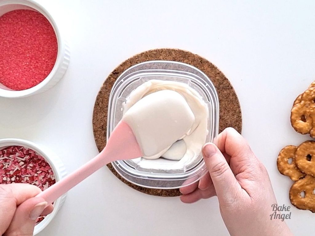 Stirring melted white chocolate with a pink spatula.