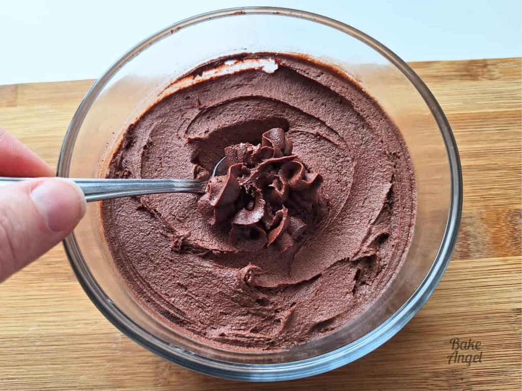 A bowl of Stable Dairy-Free Chocolate Buttercream with a spoon in the top.