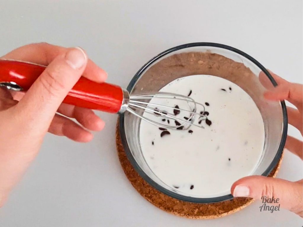 A whisk being used to combine hot coconut cream and chocolate chips to make Dairy Free Chocolate Ganache.