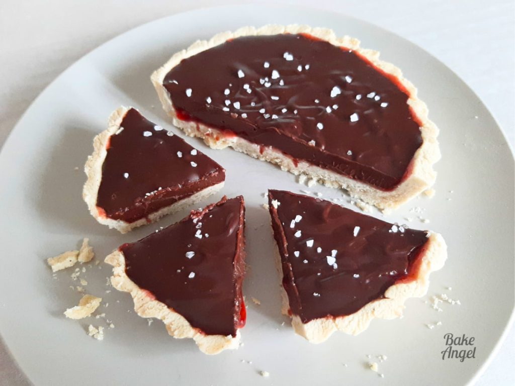 A Chocolate Ganache Mini Tart topped with coarse sea salt on a plate. .