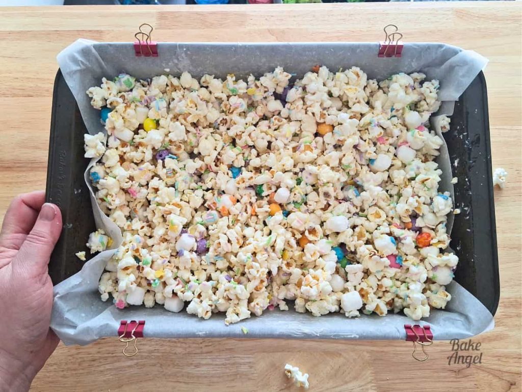 Finished Easter Bunny Bait popcorn spread in pan with chocolate and sprinkles.