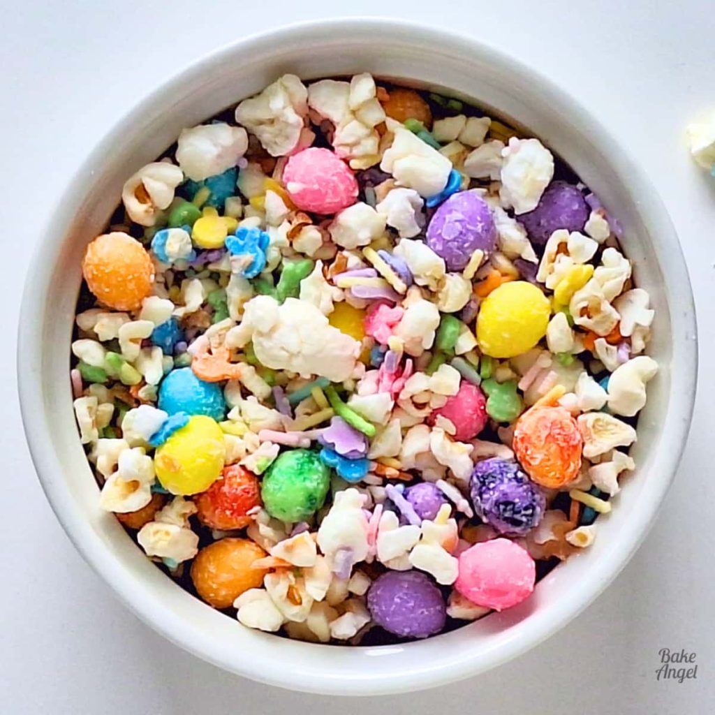 Current image: Close up of a bowl of Easter Bunny Bait Popcorn with colourful sprinkles and Easter egg candies.