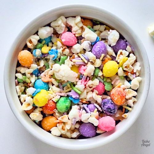 Close up of a bowl of Easter Bunny Bait Popcorn with colourful sprinkles and Easter egg candies.
