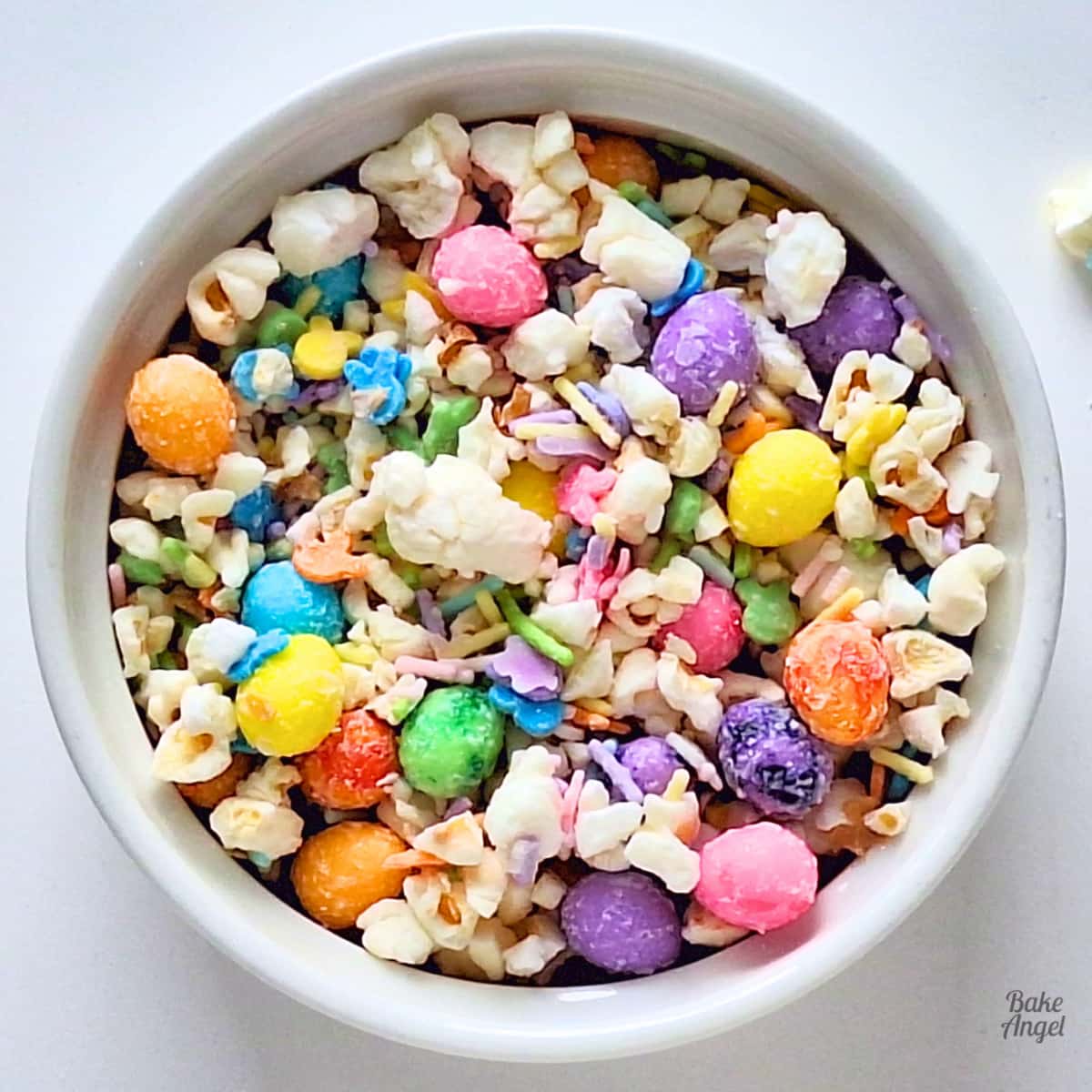 Close up of a bowl of Easter Bunny Bait Popcorn with colourful sprinkles and Easter egg candies.