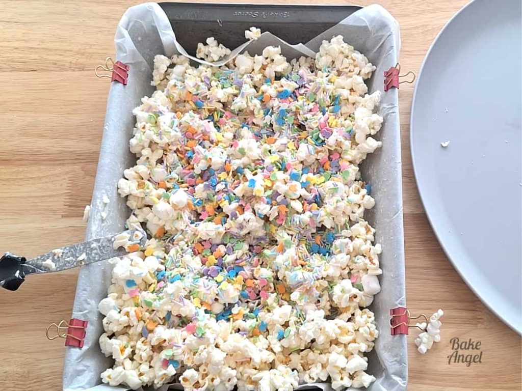 Adding Easter sprinkles to bunny bait popcorn mixture.