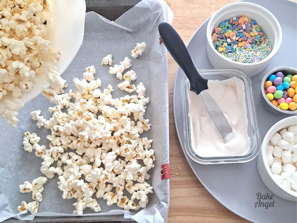Freshly popped popcorn spread in a baking pan for bunny bait popcorn.