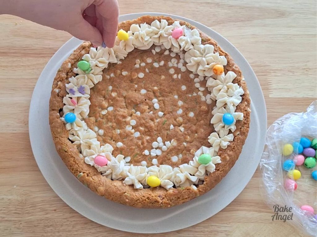 Adding sprinkles to a decorated easter cookie cake.