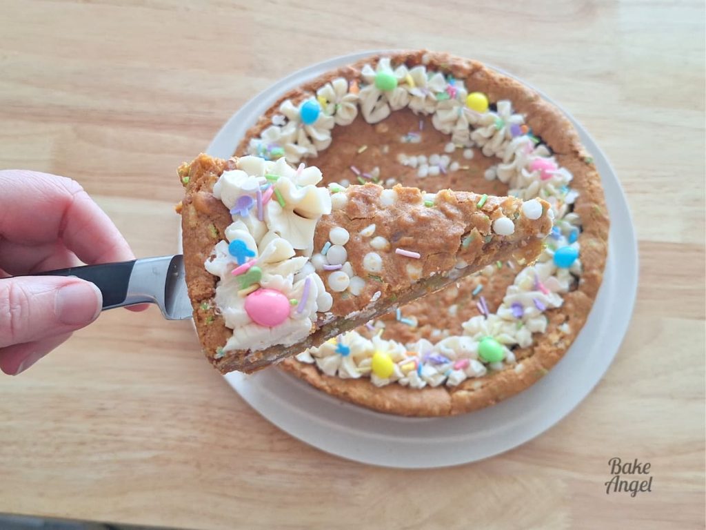Close up of a slice of easter cookie cake on a knife, held above the rest of the cookie cake on a plate.