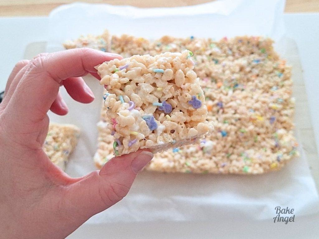 Close up of an Easter Rice Krispie Treat square being held above the slab of treats on parchment paper.